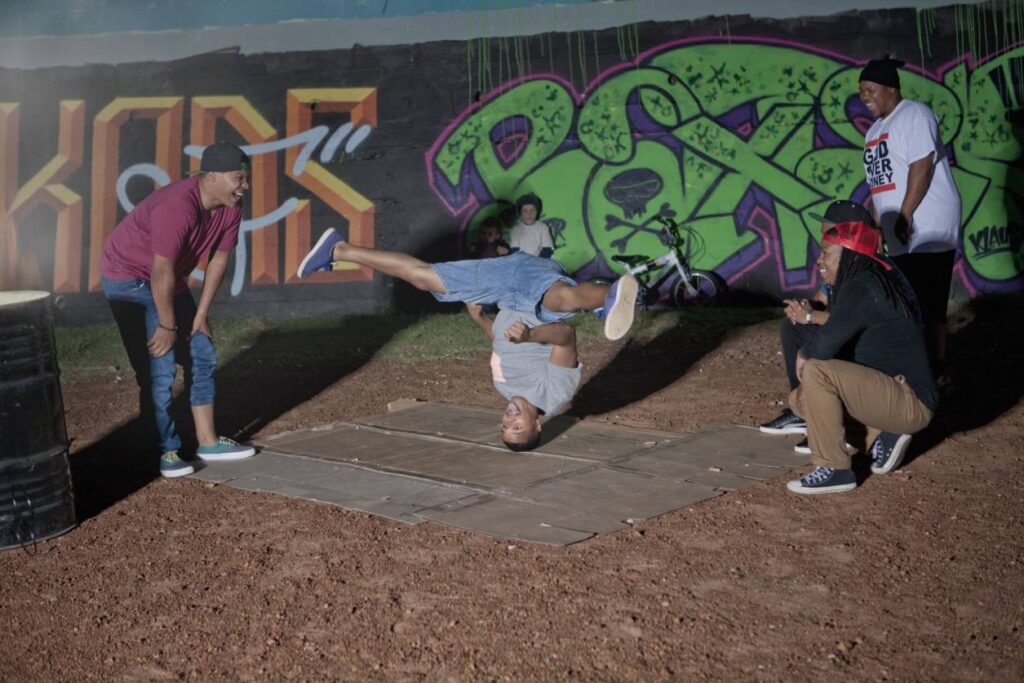 hip hop guy spinning on his head in front of his homeboys